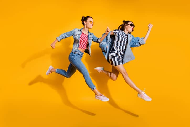 Full legs length body size portrait of two beautiful attractive glad positive grinning good-dressed lady in glasses spectacles isolated on yellow vivid background run away together