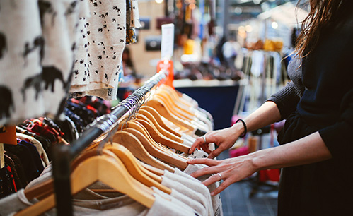 Goodwill AZ | Someone looking through clothes on hangers on the rack