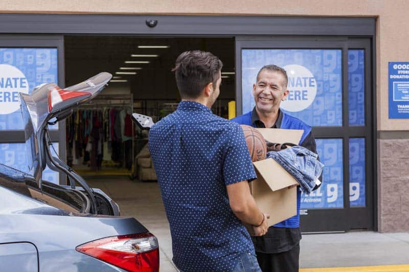 Goodwill AZ | Man passing a box of donations off