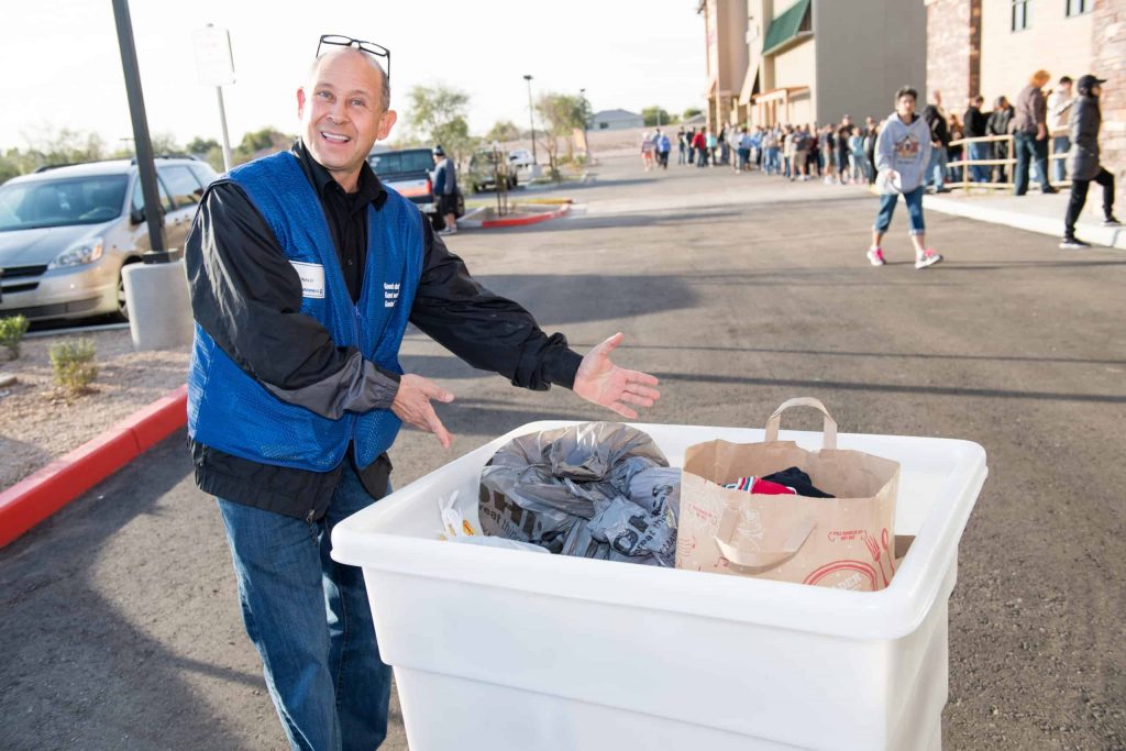 Goodwill AZ | Employee standing next to a bin full of donations