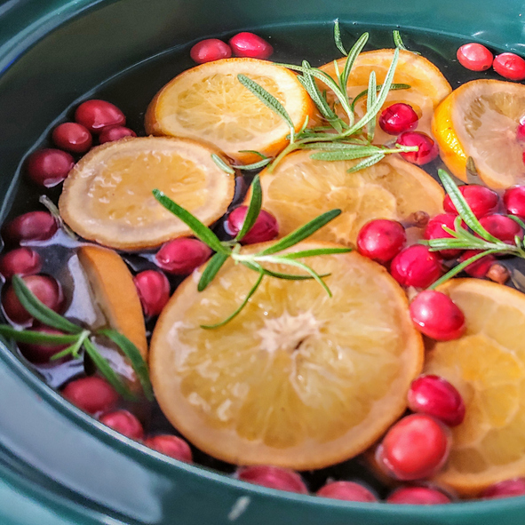 Cranberries, cinnamon, cloves, rosemary, oranges and nutmeg in a crockpot