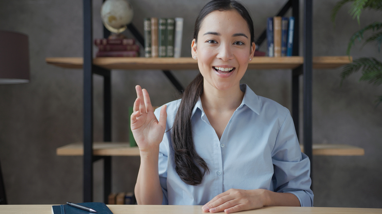 smiling lady looking straight on and lifting her hand while she speaks