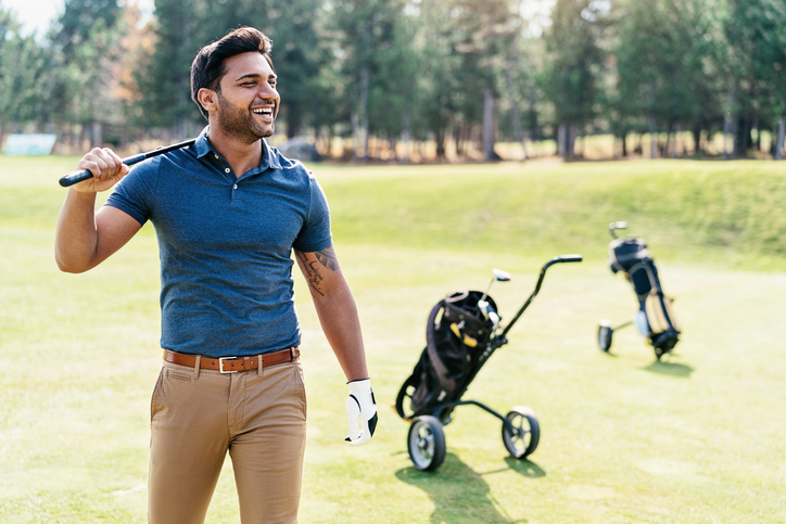 man smiling walking on a golf course
