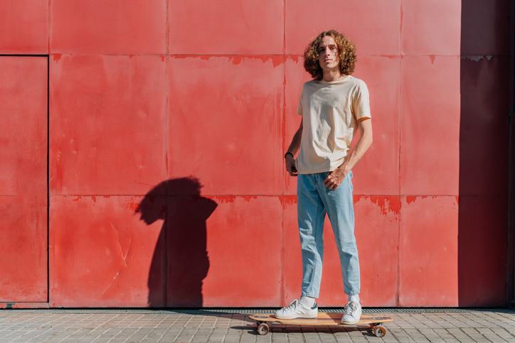 horizontal portrait of a caucasian man standing on the top of his skateboard