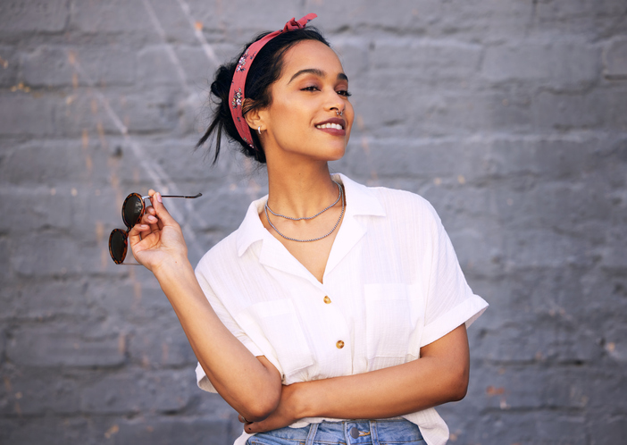 Women in a white shirt smiling holding sunglasses