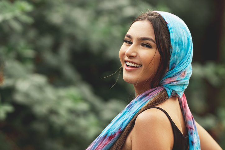 young woman smiling wearing a scarf around her head