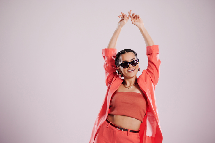 woman with her arms raised in the air wearing crop top and sunglasses