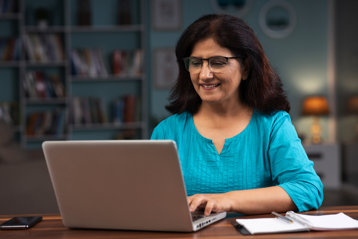 Older woman smiling while typing on a laptop