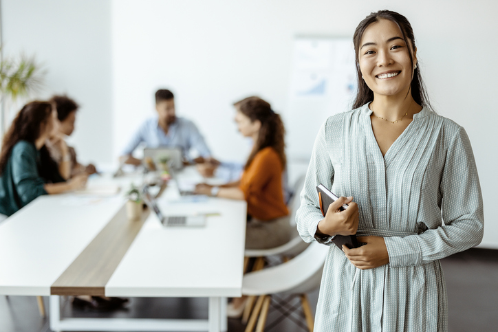 woman smiling in an office room wearing long dress