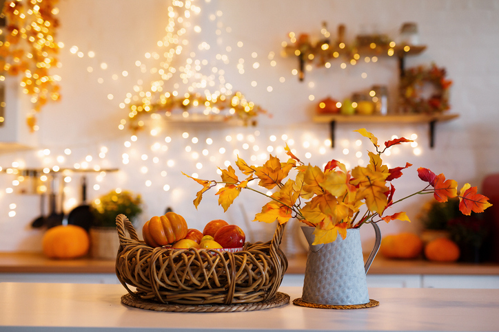 Autumn kitchen interior. Red and yellow leaves and flowers in the vase and pumpkin on white background.
