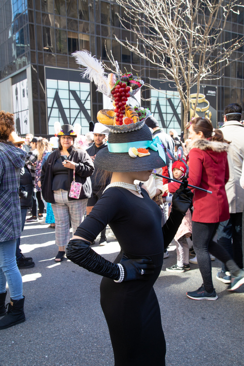 girl dressed in long black dress with a bonnet and posing for the camera as main character of Breakfast at Tiffany's