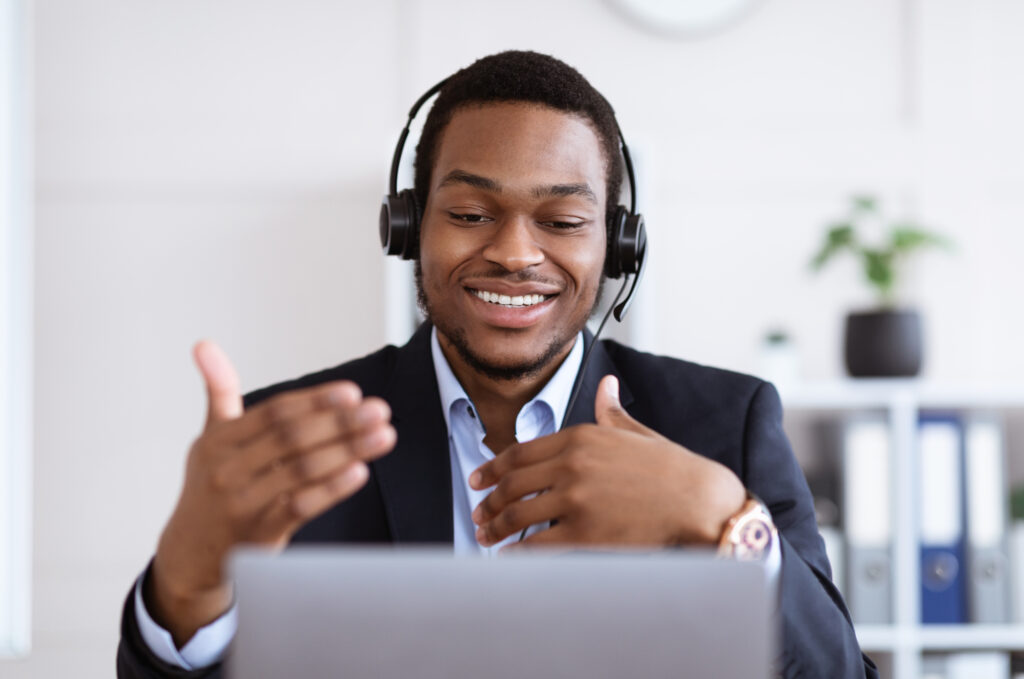 Man in a suit wearing headphones and talking on a computer