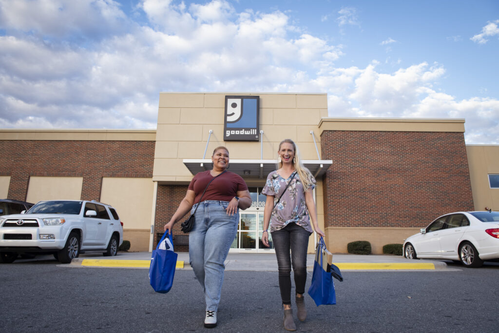 2 women walking out of a Goodwill with full shopping bags