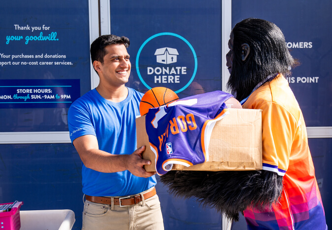 the PHX suns mascot handing a box over to a Goodwill employee