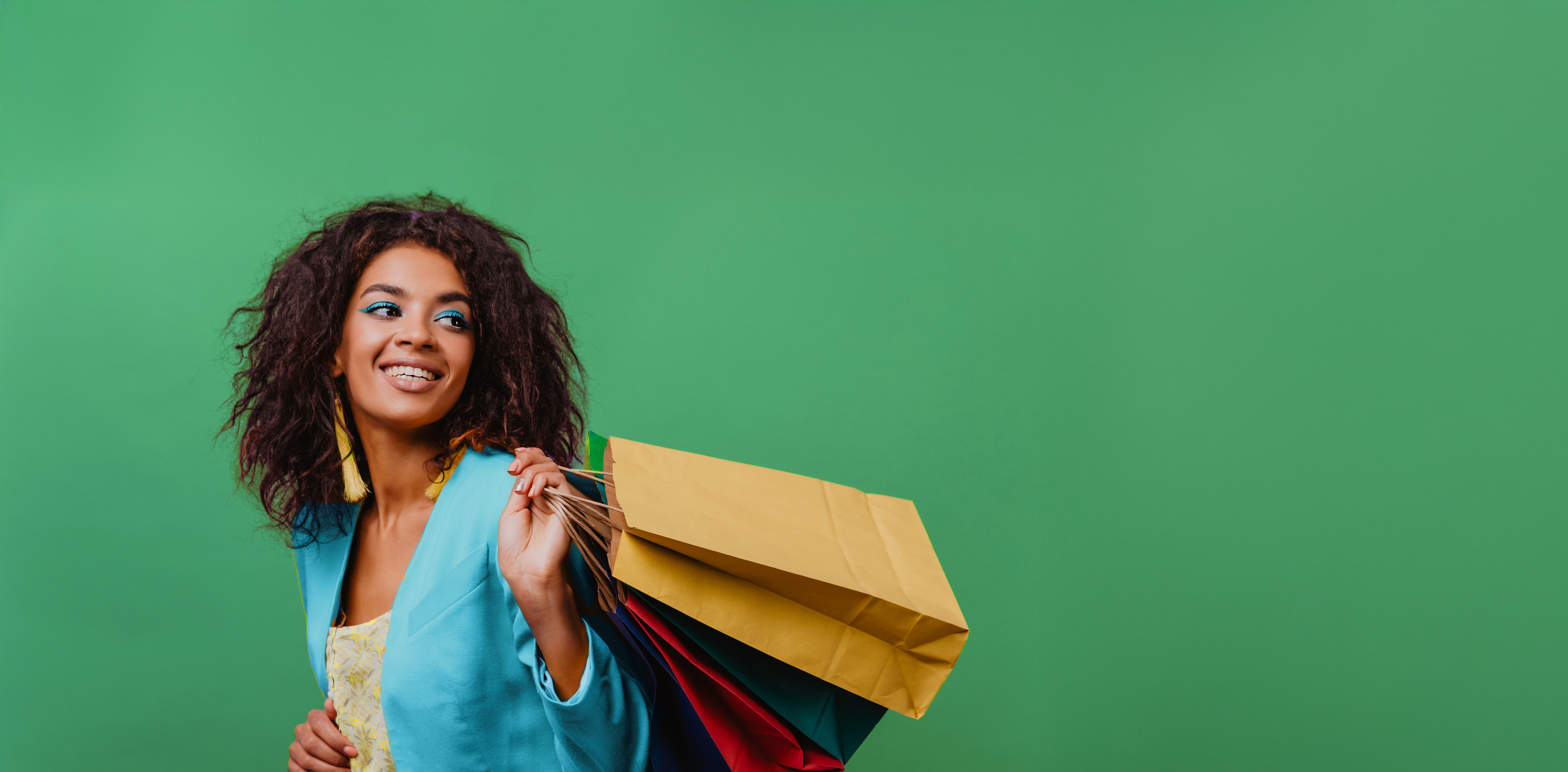 Woman with blue blazer smiling holding shopping bags over her shoulder