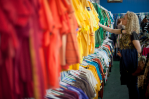 Woman shopping clothing racks in a Goodwill store