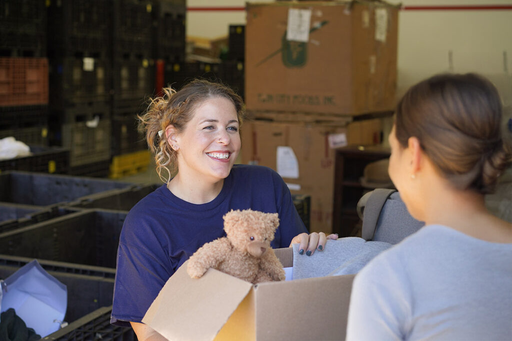 A women handing a box of donations to a Goodwill employee