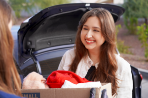 A young woman hands off a box of donations to a donation attendant