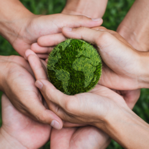 Hands hold a small green planet Earth