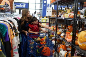 A mom and a young girl walking the Halloween aisles of Goodwill