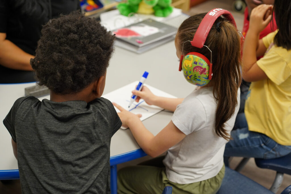 Young kids coloring on a whiteboard