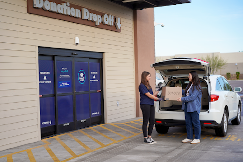Two women taking a donation box out of a car at a Goodwill